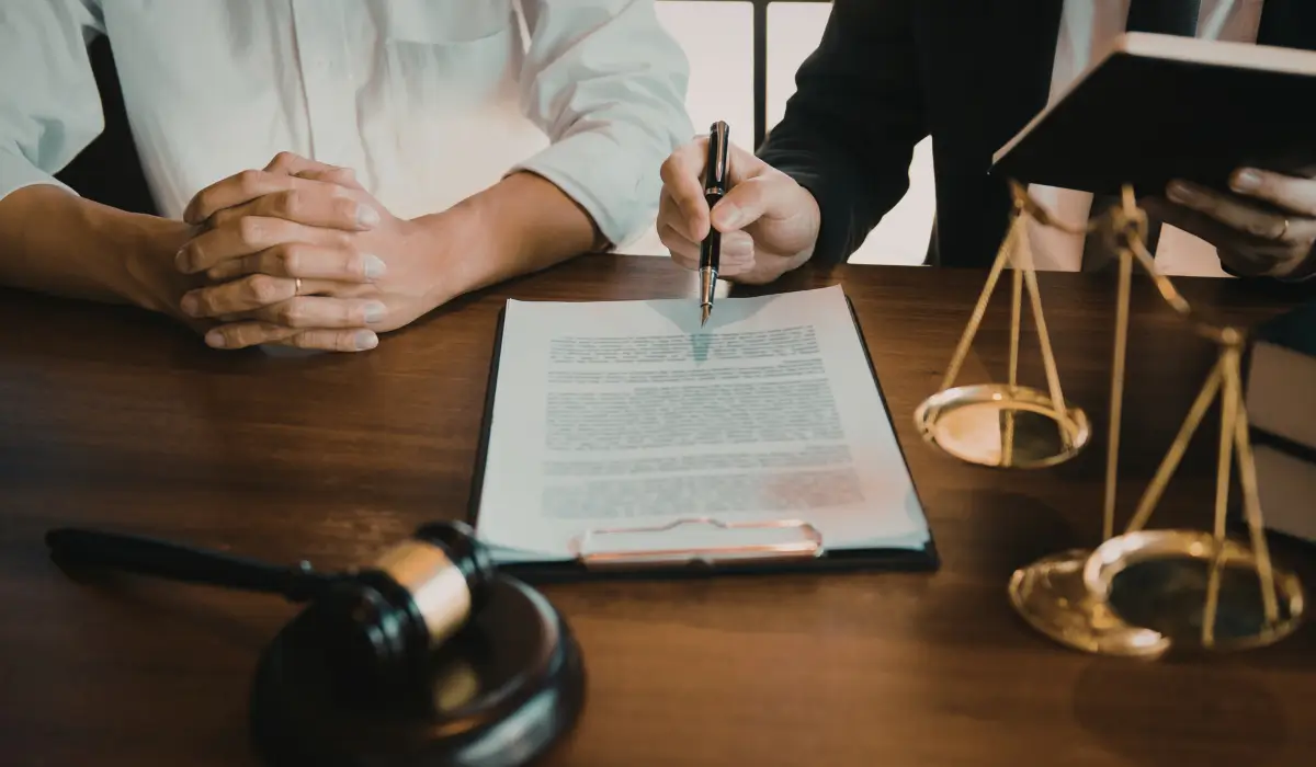 Client and attorney reviewing license reinstatement consultation documents in legal office with justice scale.