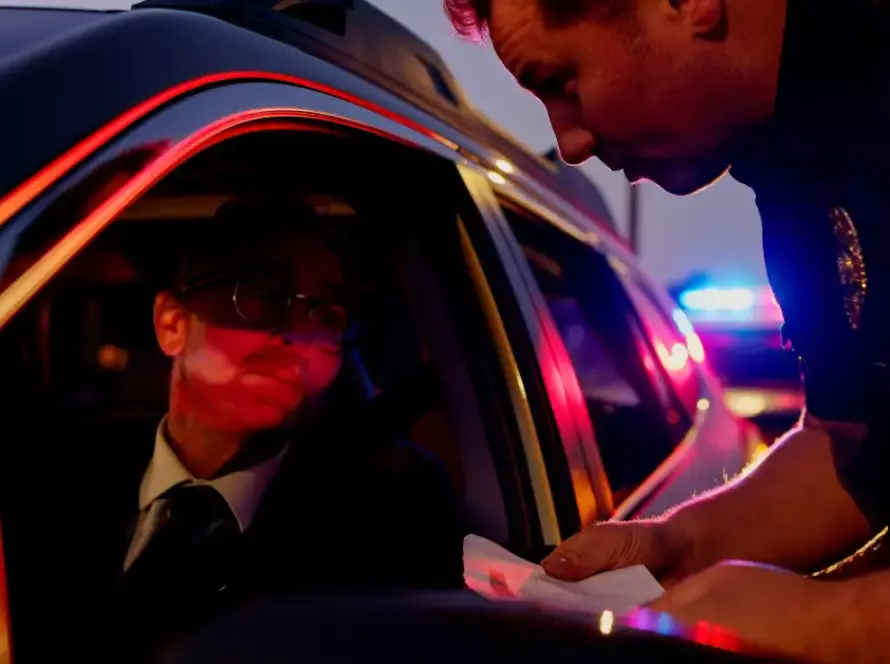 Illinois License Suspension Attorney traffic stop showing a police officer reviewing documents during a nighttime roadside investigation.