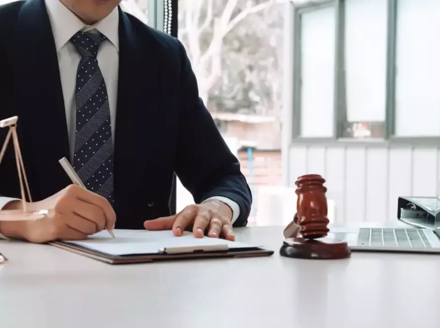 A professionally dressed attorney writes on documents at a desk with a judge’s gavel and scales of justice nearby, preparing for an Illinois Secretary of State hearing related to driver’s license reinstatement.